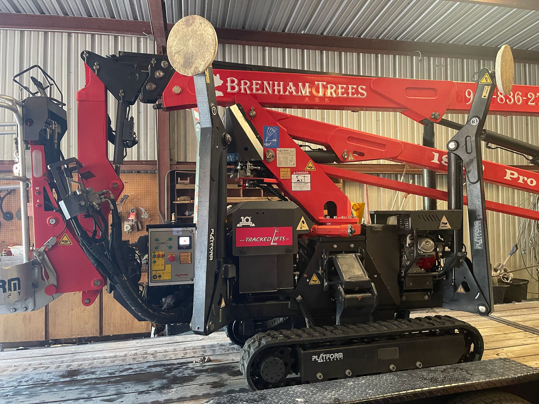 Red Brenham Trees tracked spider lift on its trailer in the shop